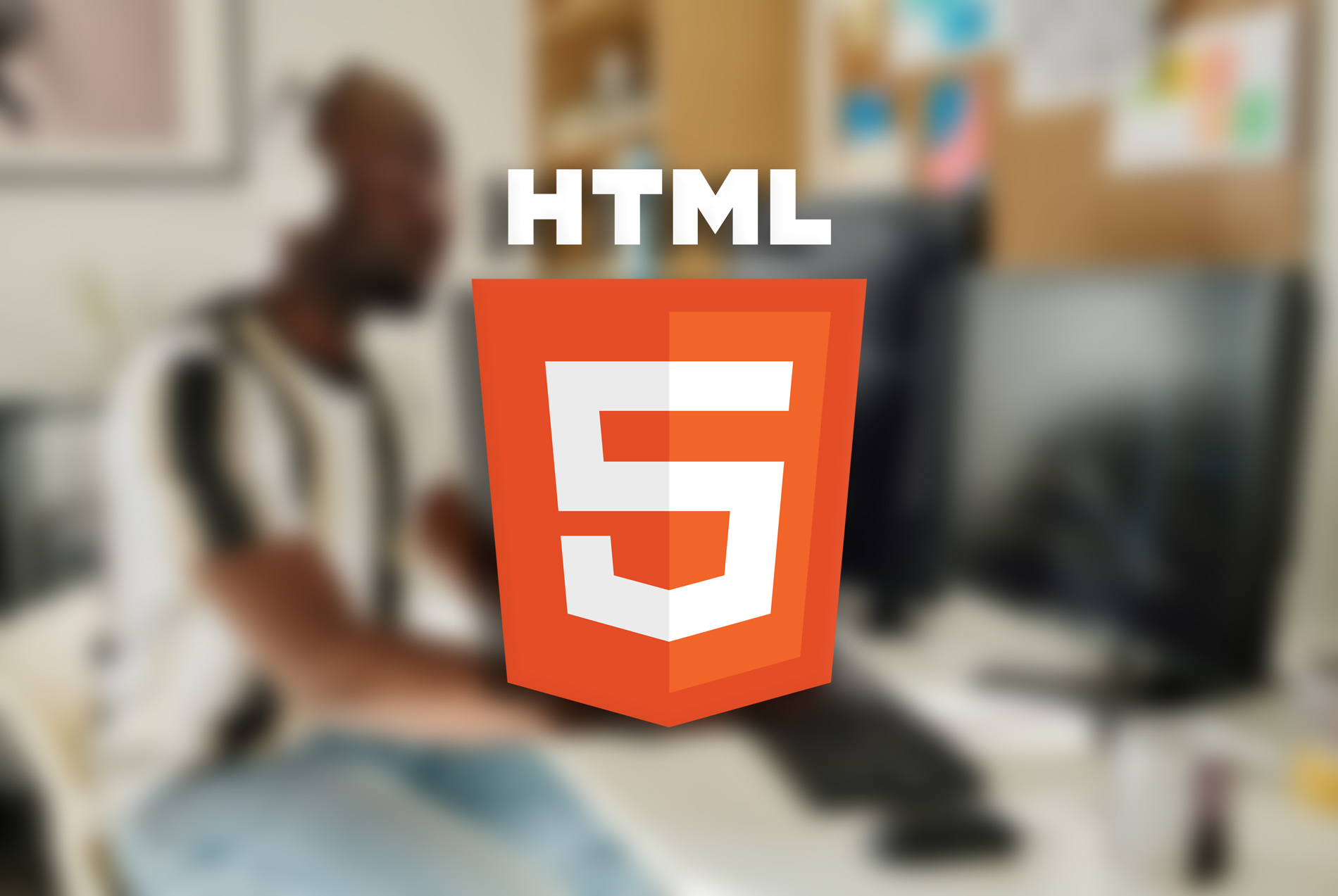 Símbolo do HTML5 sob fundo desfocado de pessoa utilizando PC.