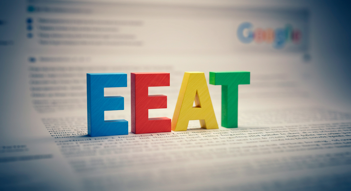 Sigla EEAT em frente uma página do Google embaçada.