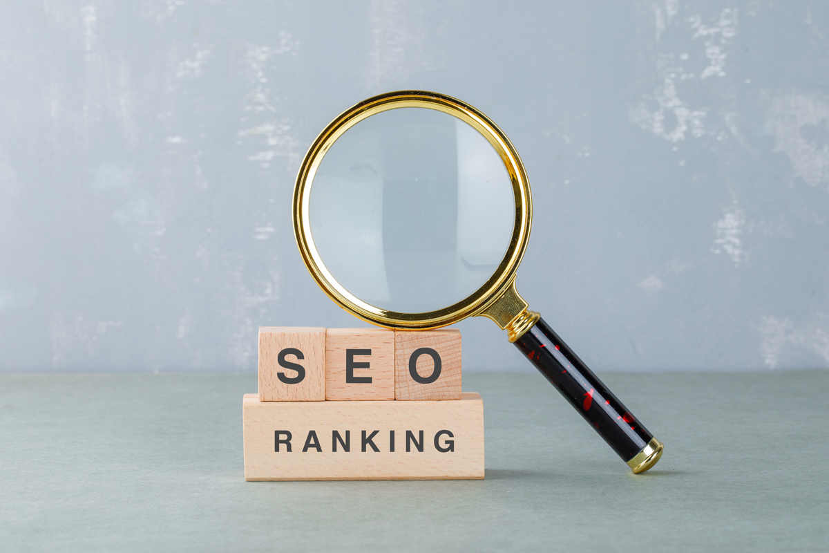 Conceito de SEO para B2B representado por lupa sobre blocos de madeira com as palavras SEO e ranking, destacando a análise e o posicionamento nos resultados de busca corporativos.