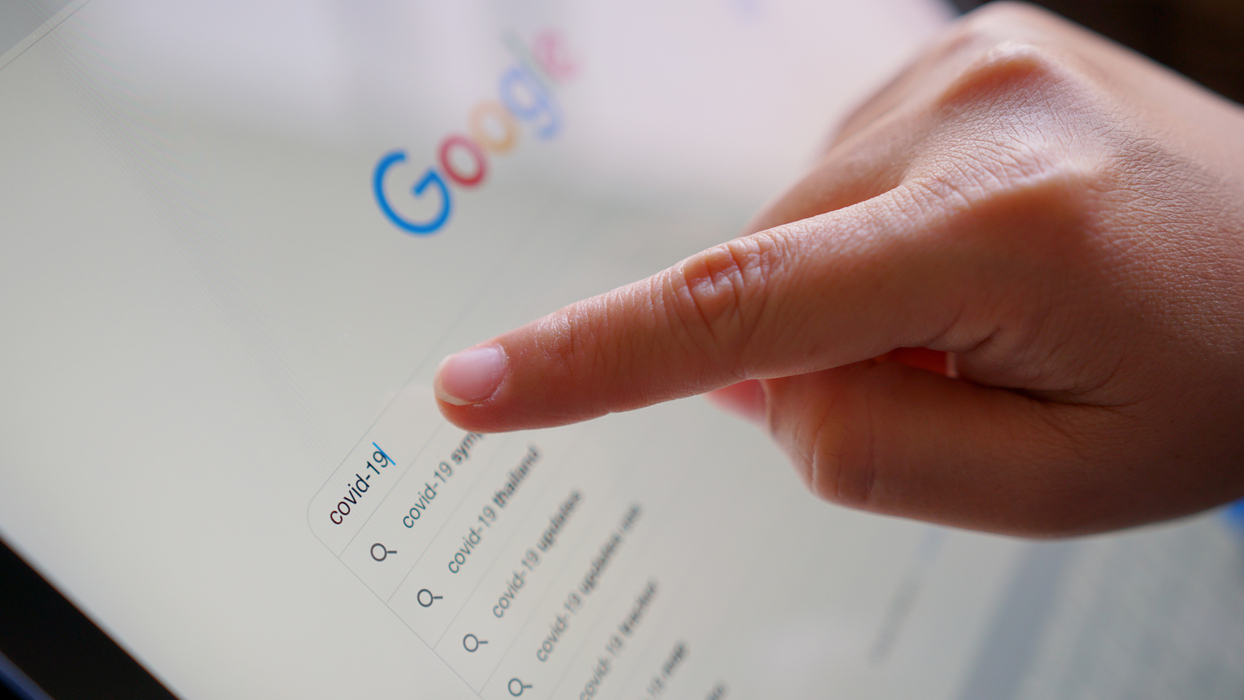 Mão pesquisando no Google em um tablet; barra de busca com sugestões. Exemplo prático de como aplicar SEO para imagens com contexto real