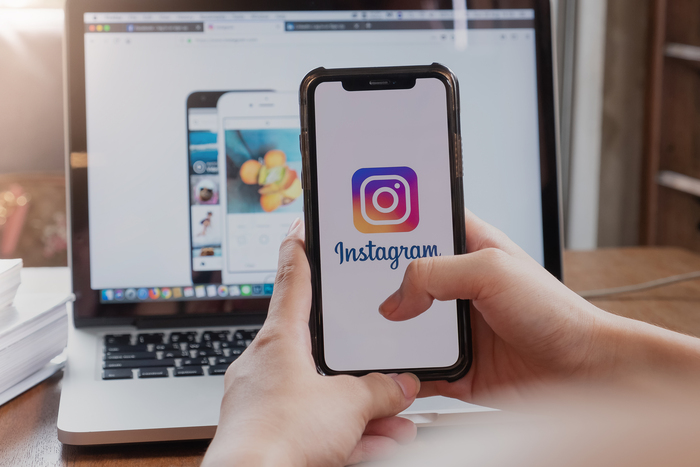 Usuário abrindo o Instagram no smartphone, reforçando a presença digital e o calendário de conteúdo da marca.