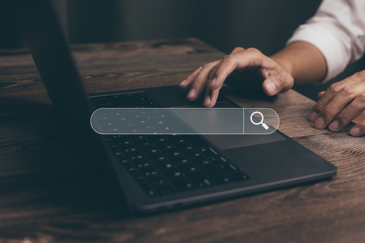 Mãos digitando em um notebook com barra de busca na tela, representando problemas de navegação e páginas de produto que não vendem por falta de informações claras.